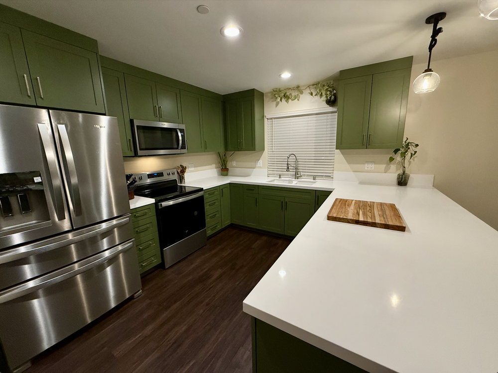 Modern kitchen with green cabinets and white countertops
